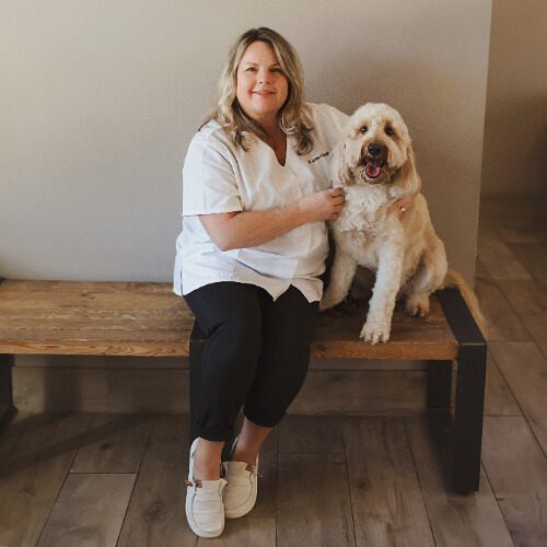 Female veterinarian with long blonde hair posing with large dog with light curly hair