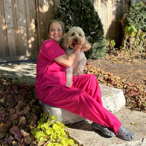 female wearing pink scrubs and posing with large dog