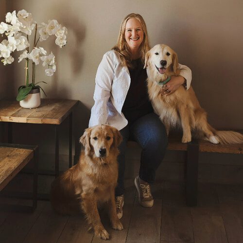 female veterinarian sitting with 2 golden retrievers